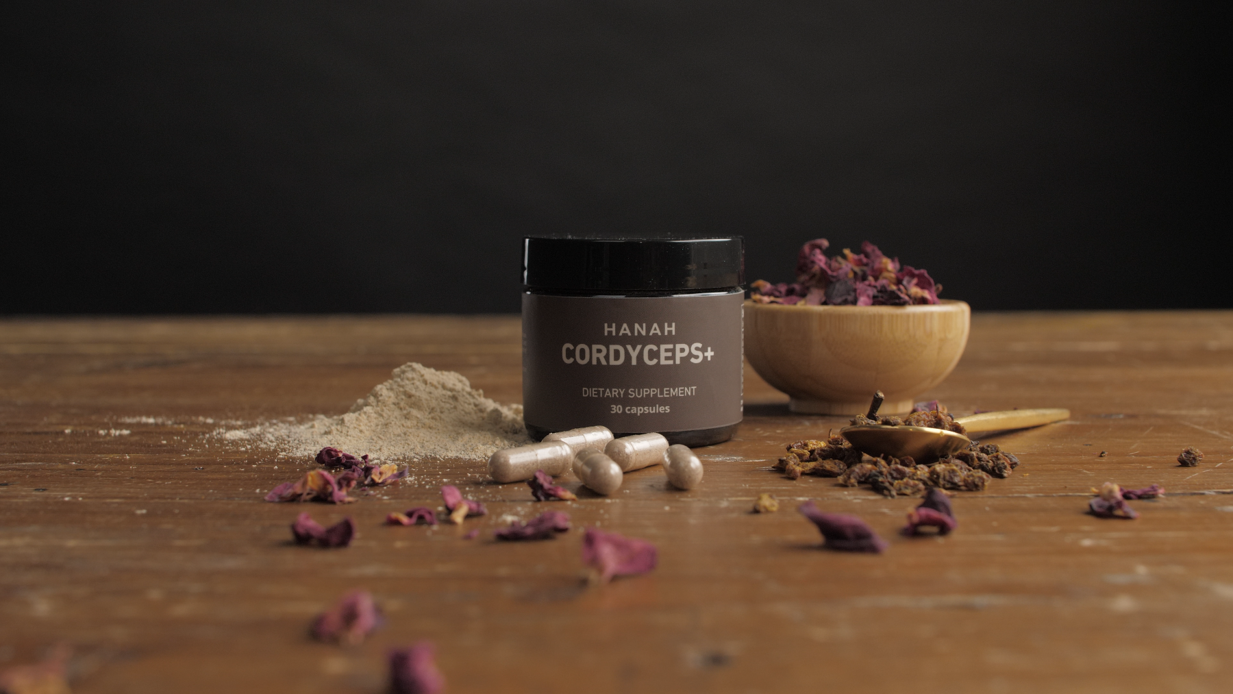 Jar of HANAH Cordyceps, a dietary supplement, surrounded by its ingredients and capsules