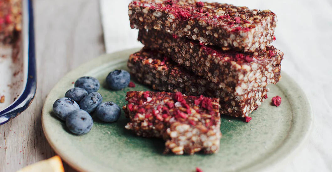 Crispy cacao hemp bars with HANAH Ashwagandha, a twist on the classic rice crispy treat on a green plate next to some blueberries