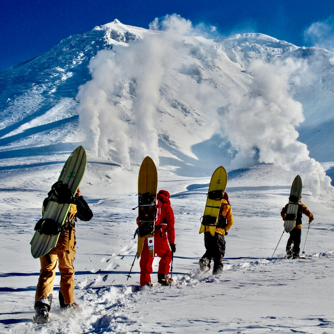 Four snowboarders trekking through the snow symbolizing the many HANAH Heroes utilizing HANAH products in their lives