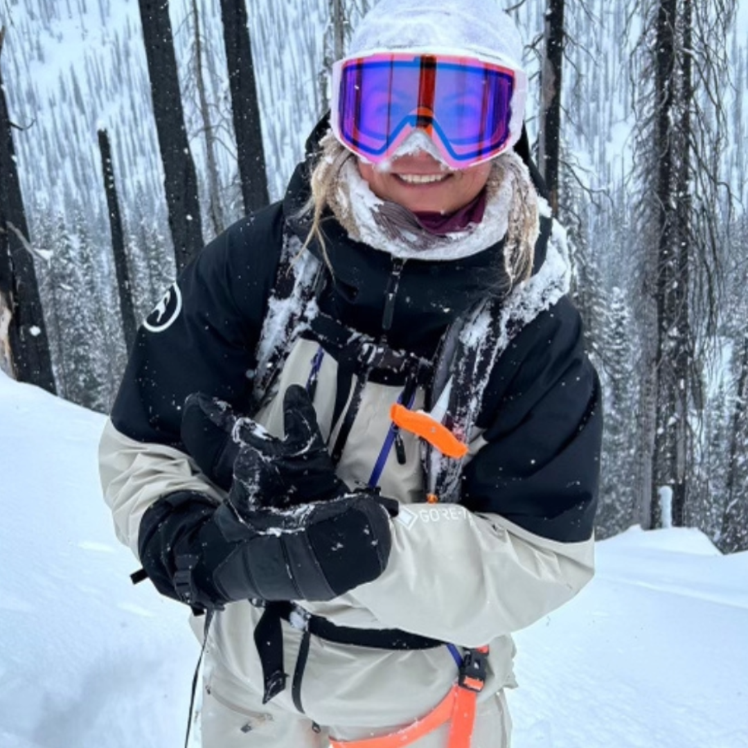 Pro snowboarder Annie Boulanger stands on a snowy slope in the backcountry in full snowboarding attire.