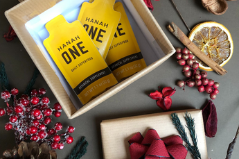 Three HANAH ONE Go-Packs in a holiday gift box surrounded by holiday decorations.