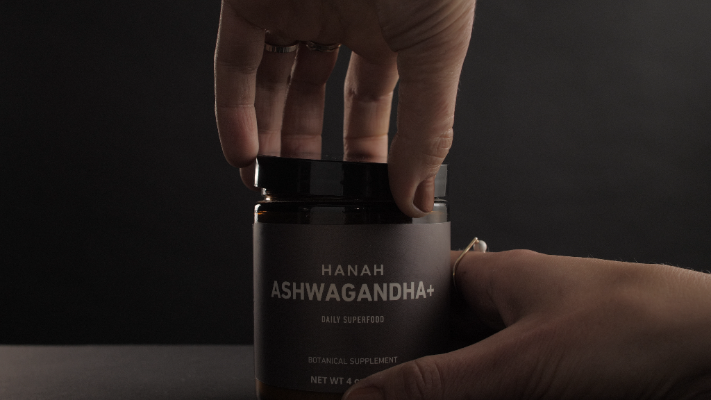 Set of hands opening a jar of HANAH Ashwagandha, a daily superfood