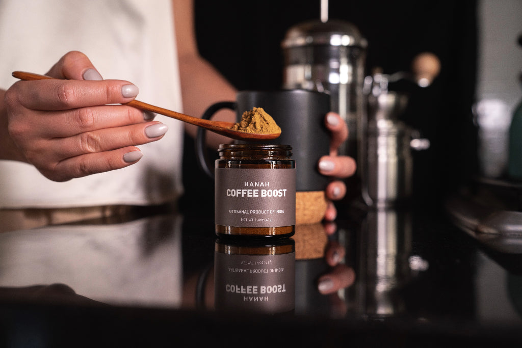 Spoonful of HANAH Coffee Boost, an artisanal product, held above its jar