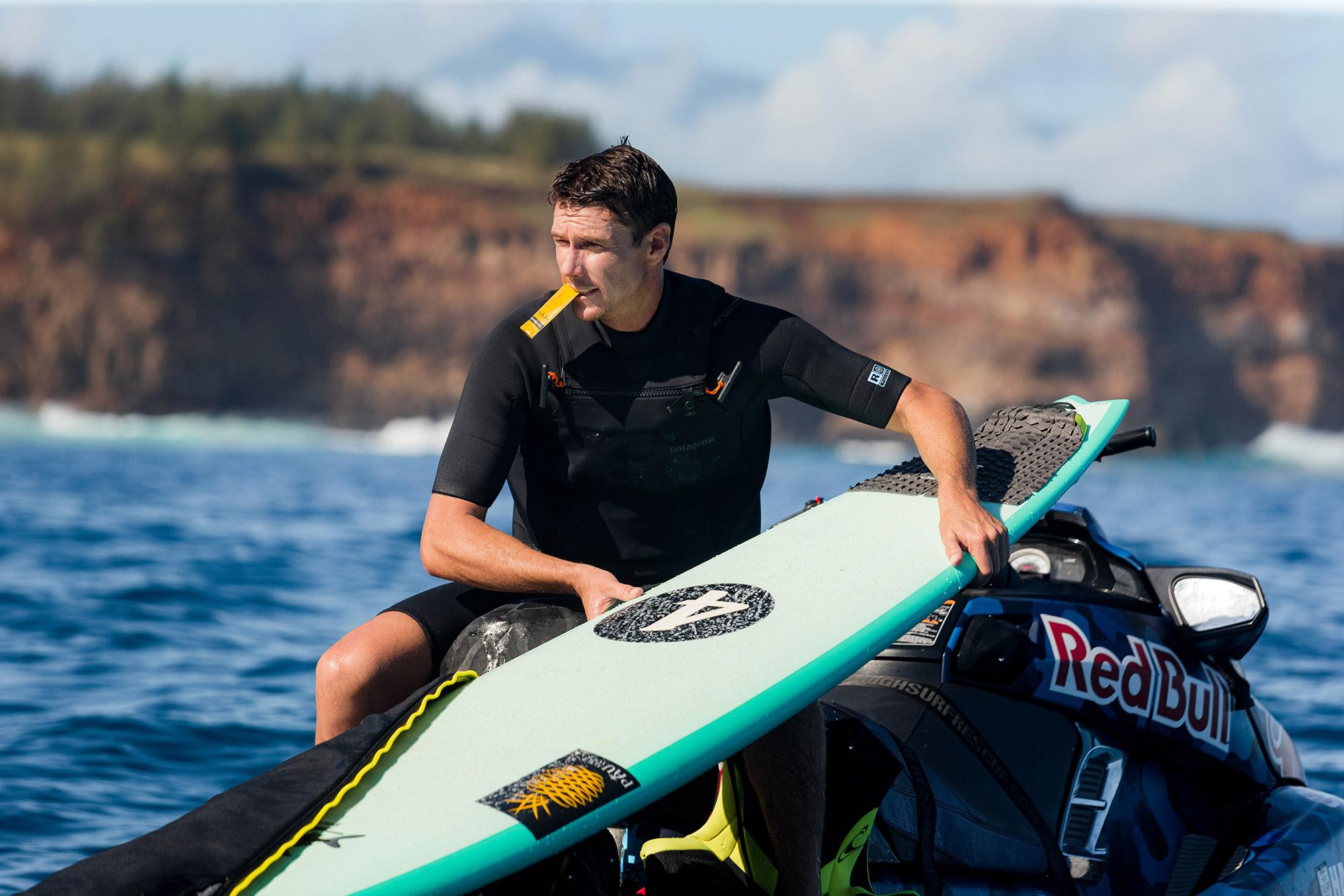 Hanah Hero Ian Walsh getting ready to surf while fueling up with a HANAH ONE GO-PACK in his mouth